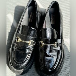 Black loafers with gold buckle detail